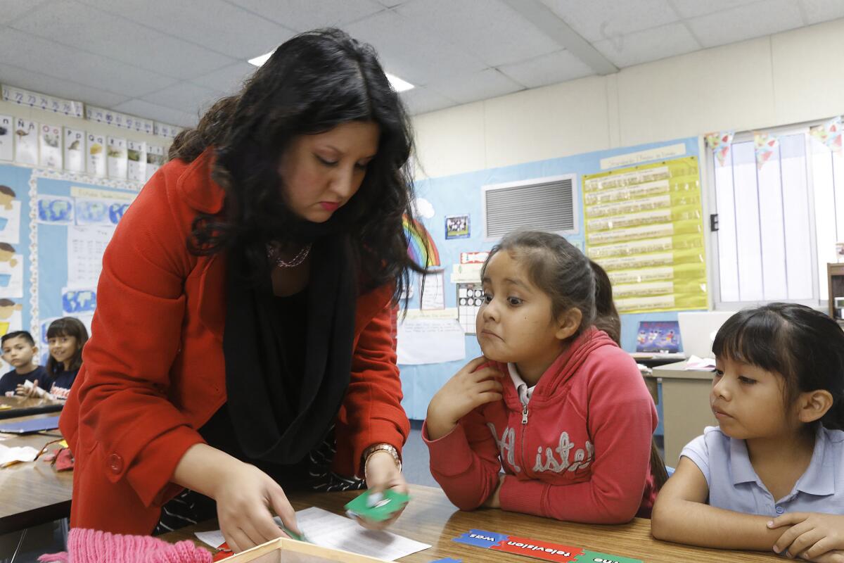 Letisia Huertado, shown in 2014, helps two first-graders learn English by constructing sentences at Parkview School in El Monte. State education officials have agreed to boost oversight of school district efforts to provide legally required services to students learning English.