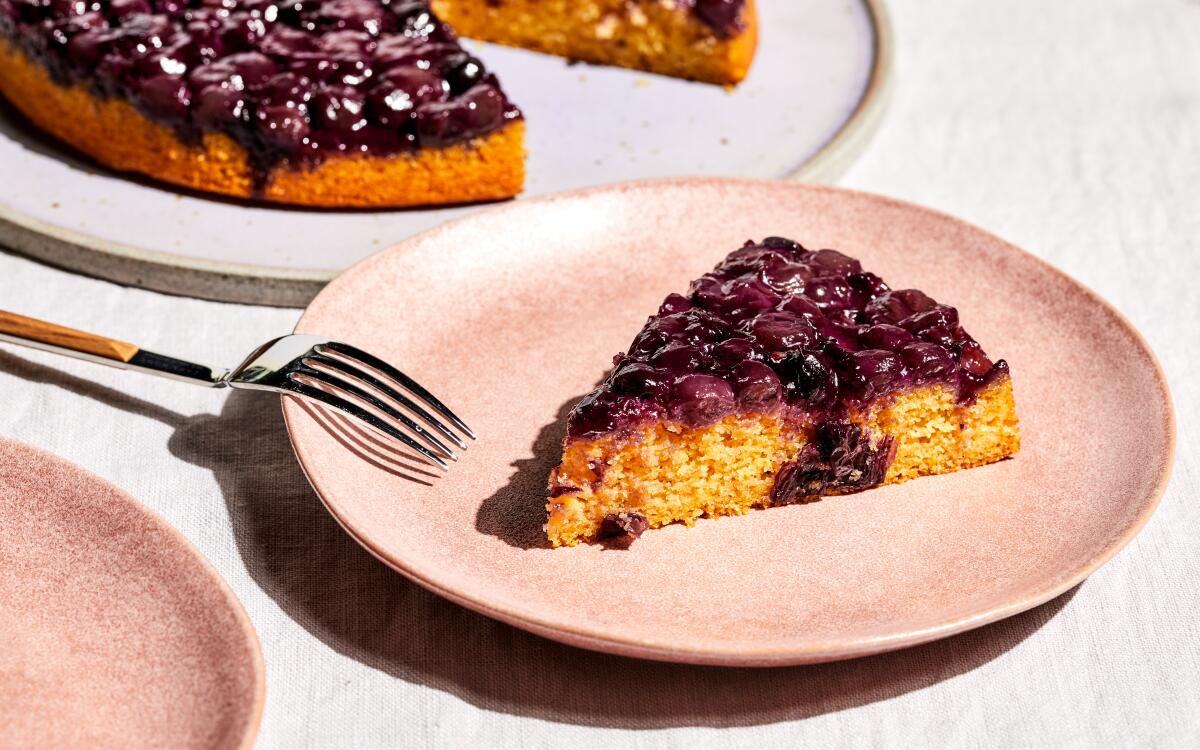 A triangular slice of yellow cake topped with fruit on a plate