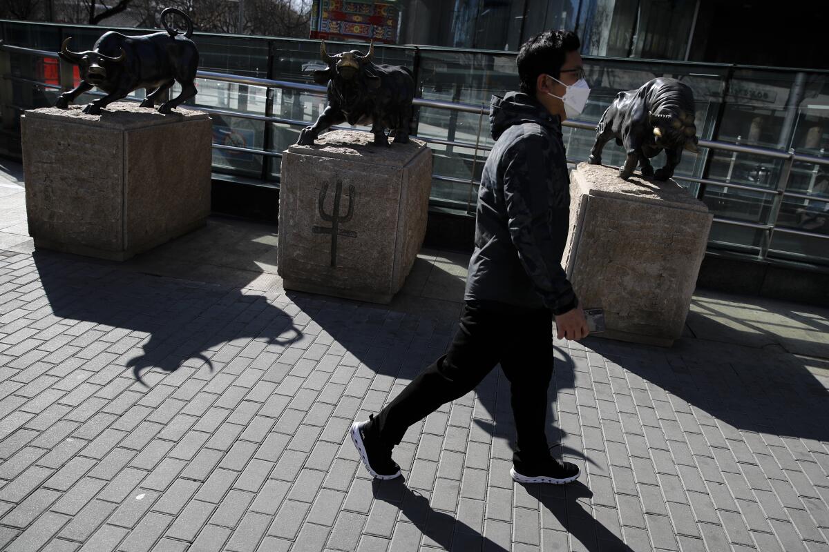 A man walks past a row of statues outside a bank in Beijing.