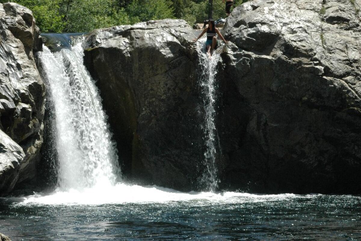 A swimmer sitting on a rock at Rainbow Pool, Yosemite National Park.