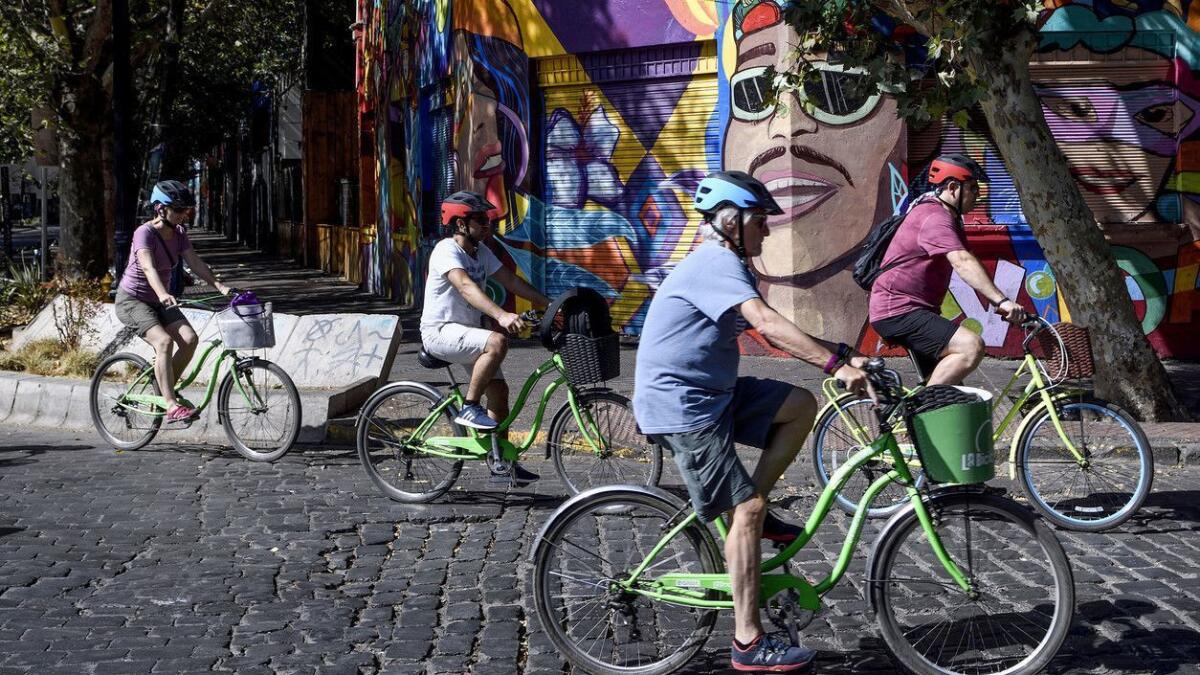 A group of tourists rides rented bicycles in the Bellavista neighborhood of Santiago, Chile, where car-free Sundays make exploring on two wheels easier.