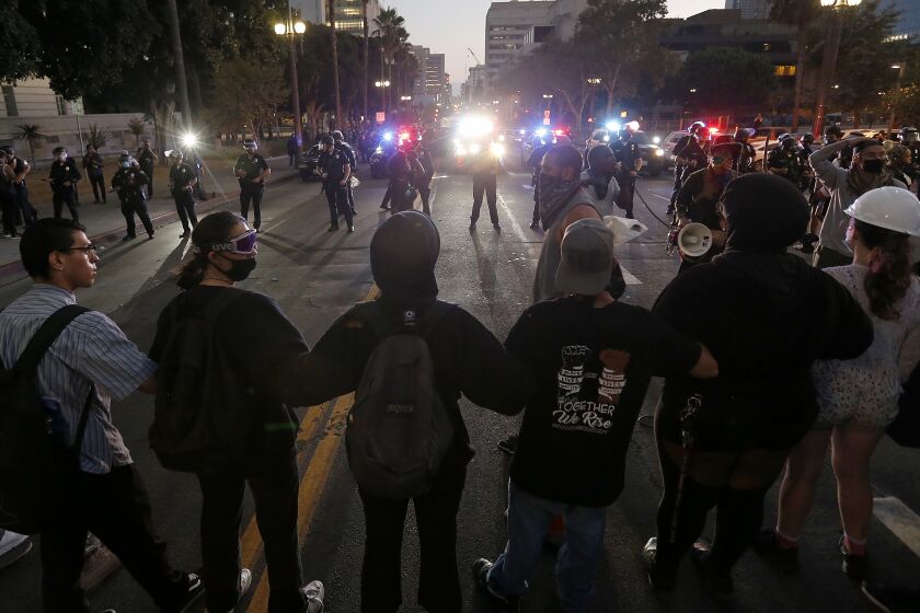 LOS ANGELES, CA - JULY 25, 2020. Protesters link arms and face off against the LAPD in front of L.A. City Hall during a Refuse Fascism demonstration on Saturday, July 25, 2020. (Luis Sinco / Los Angeles Times)