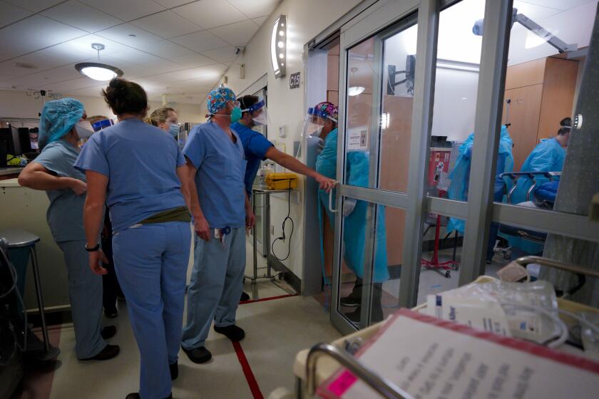 Nurses stand to assist doctors and nurses inside the negative pressure room.