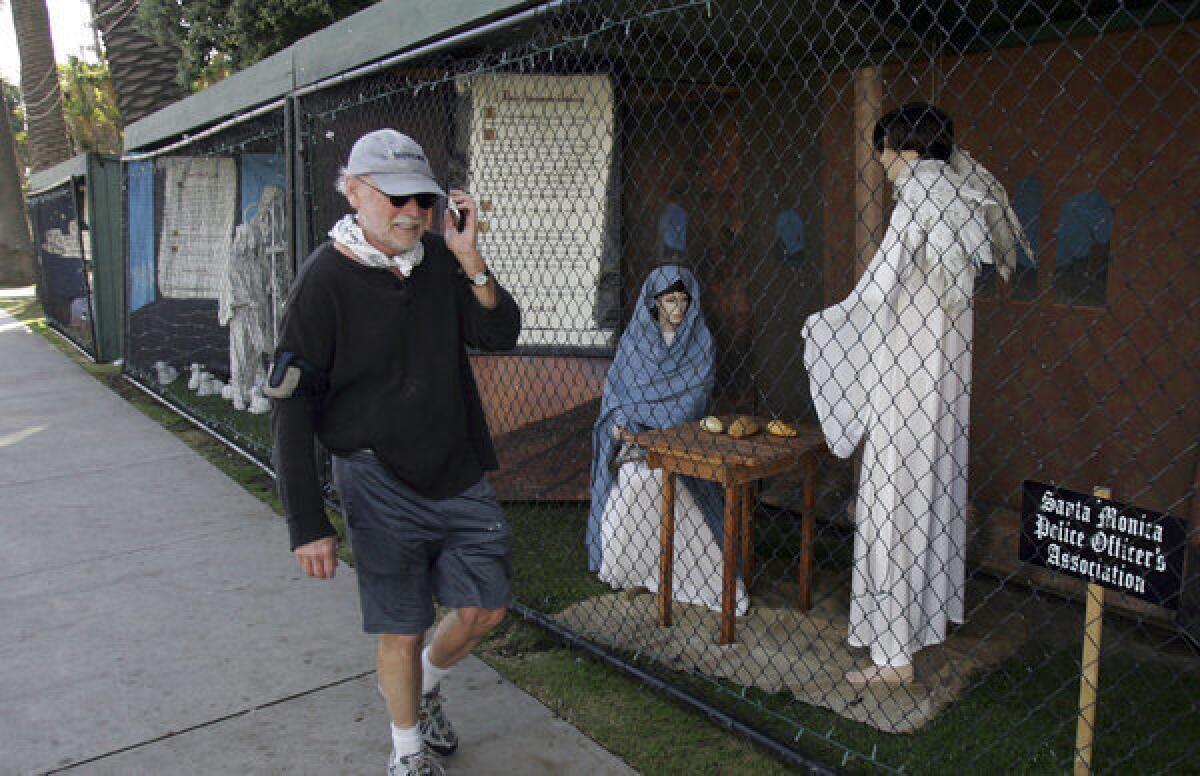 A man walks past two of the traditional Nativity scenes along Ocean Avenue at Palisades Park in Santa Monica last year.