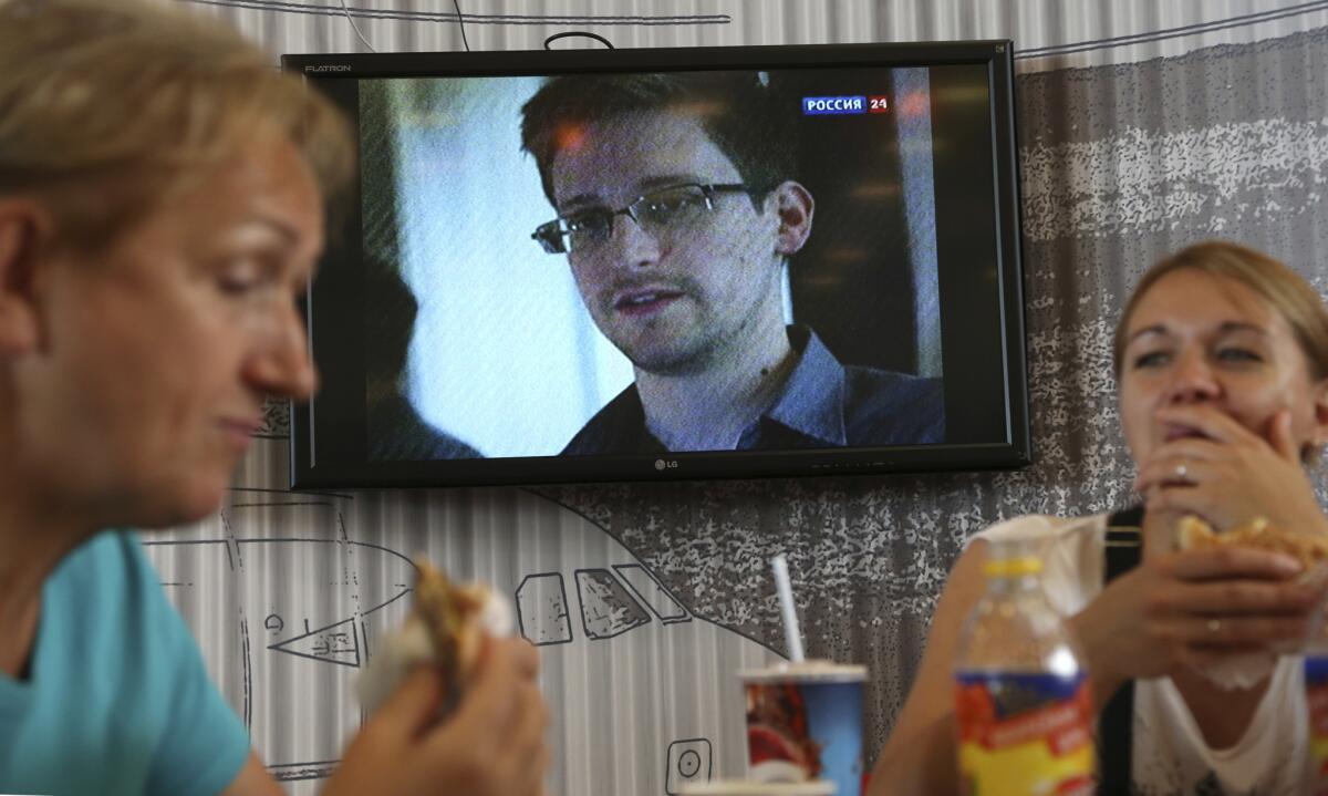 Passengers eat at a cafe in Moscow's Sheremetyevo airport Wednesday with a TV screen showing a report on Edward Snowden, who is believed to be in the airport.