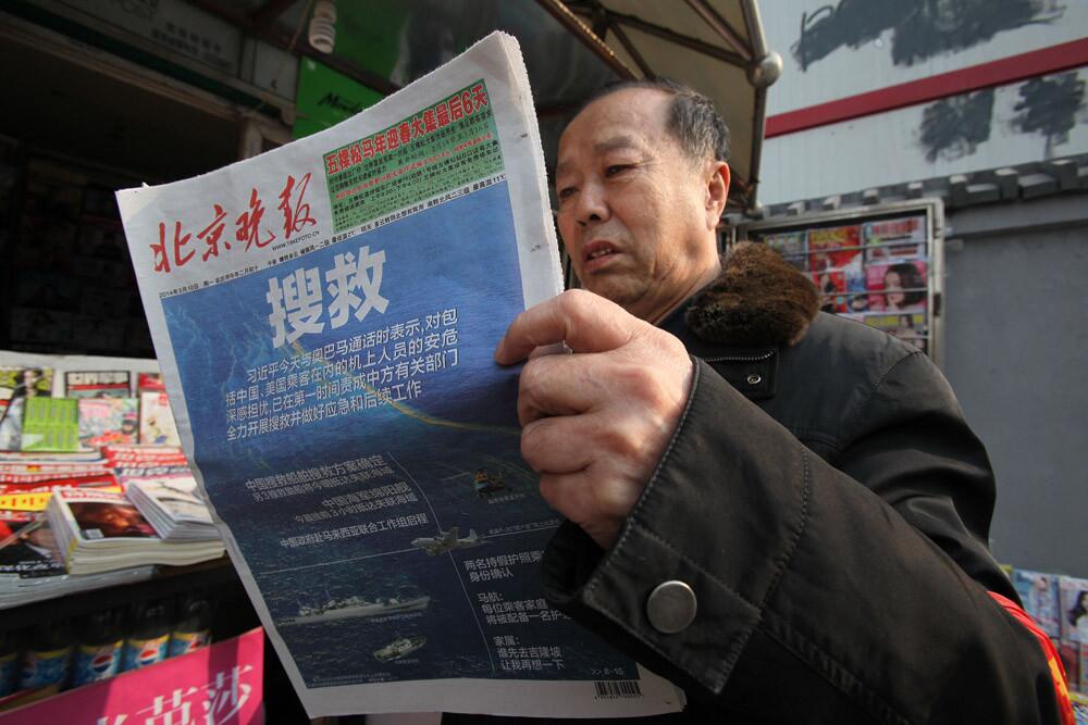 A resident reads a newspaper with reports about the missing Malaysia Airlines flight in Beijing on March 10, 2014.