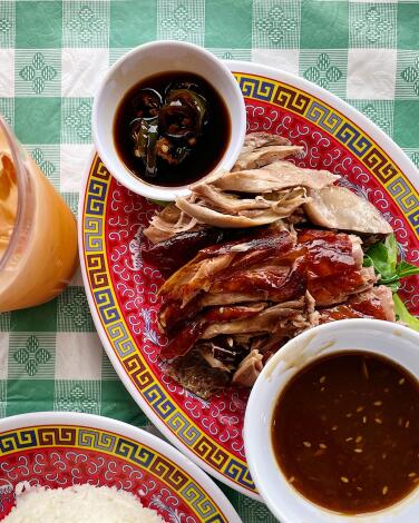 A plate of sliced roast duck with sauces and rice