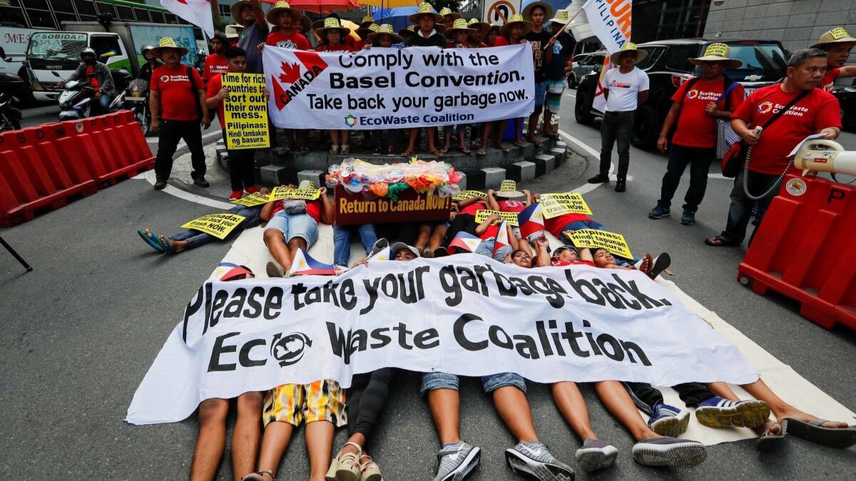 Demonstrators hold placards while lying down on the road during a protest at the Canadian Embassy in Makati, south of Manila, Philippines, May 21, 2019.