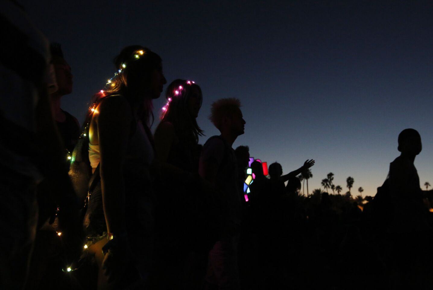 Two women wear lights on their bodies as they listen to a performance at Coachella.