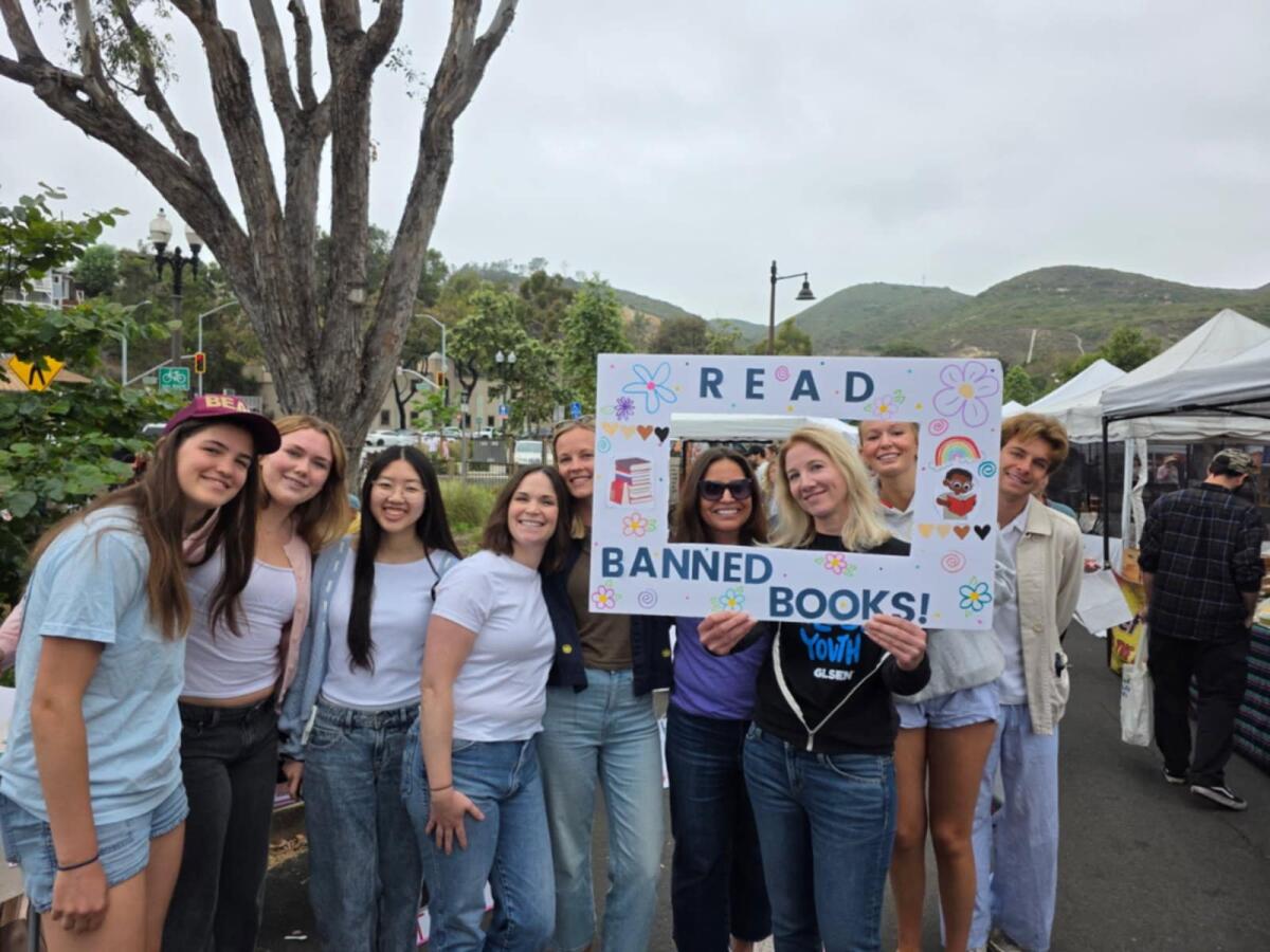 Heather Hanson, holding the selfie prop, is joined by local educators and students at a Teach Truth pop-up in Laguna Beach.