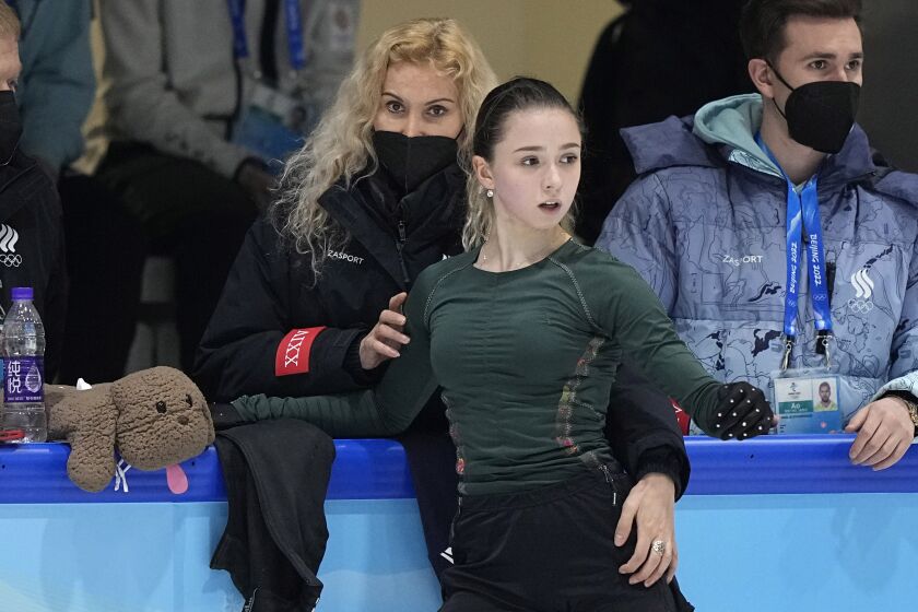 FILE - Coach Eteri Tutberidze, left, talks to Kamila Valieva, center, of the Russian Olympic Committee, during a training session at the 2022 Winter Olympics, on Feb. 13, 2022, in Beijing. Russian President Vladimir Putin has awarded figure skating coach Eteri Tutberidze one of the country’s highest honors. It comes nearly a year after a doping case involving one of her top skaters overshadowed the Winter Olympics. A presidential decree published lists Tutberidze among three people awarded the Order of Alexander Nevsky “for ensuring the successful training of athletes who achieved high sporting accomplishments” at the Winter Olympics in Beijing in Feb. 2022. (AP Photo/David J. Phillip, File)