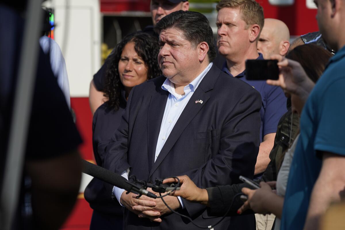 Illinois Gov. J.B. Pritzker standing with others at a news conference.