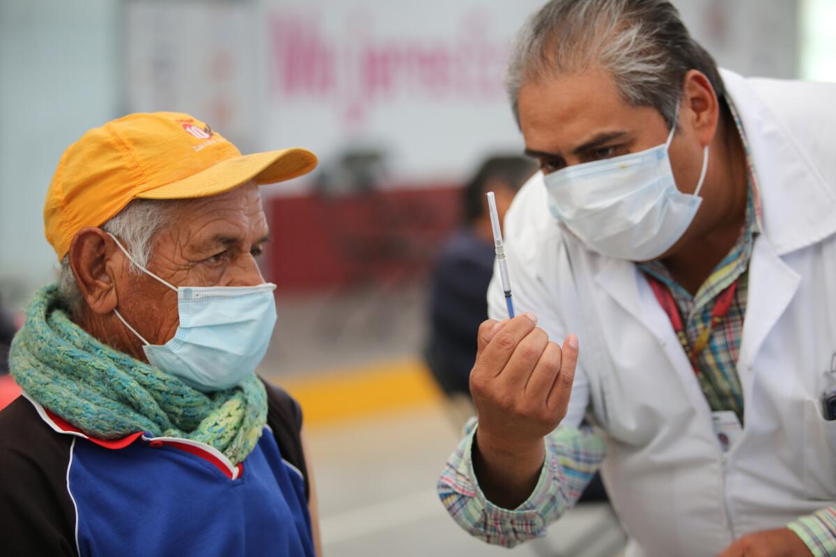 Un enfermero muestra a un anciano una jeringa preparada con una dosis de la vacuna de Sinovac