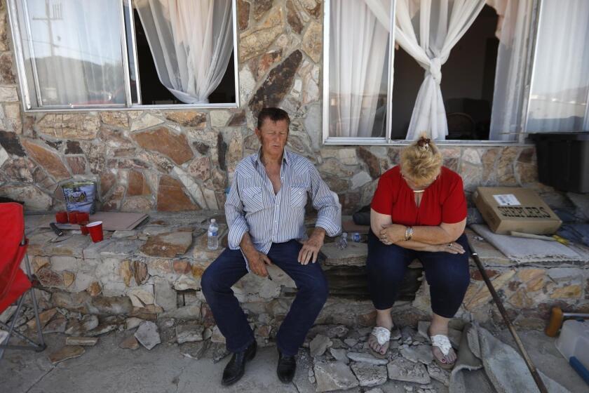 TRONA, CA - JULY 10, 2019 - Benny Eldridge, 76, and his wife Anna Sue, 75, sit in front of their earthquake damaged home in Trona on Wednesday July 10, 2019. Benny helped build the home with his father-in-law in 1961. They raised their family at the home. The house has been red-tagged and the Eldridge's will have to move to Bakersfield to live with one of their daughters. (Genaro Molina/Los Angeles Times)