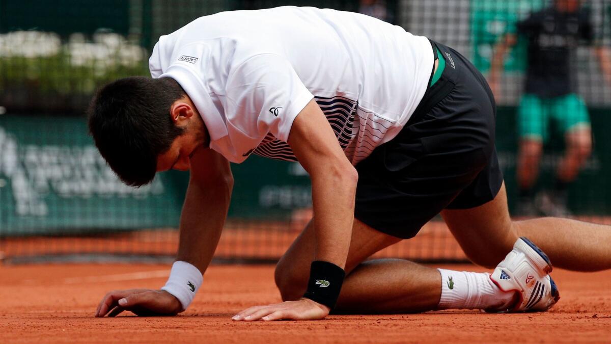 Novak Djokovic falls as he plays Dominic Thiem during the quarterfinal round of the French Open on Wednesday.