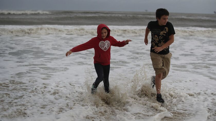 Isabella Roberson and Stanely Roberson run from the incoming waves from Tropical Storm Gordon on Tuesday in Dauphin Island, Ala.