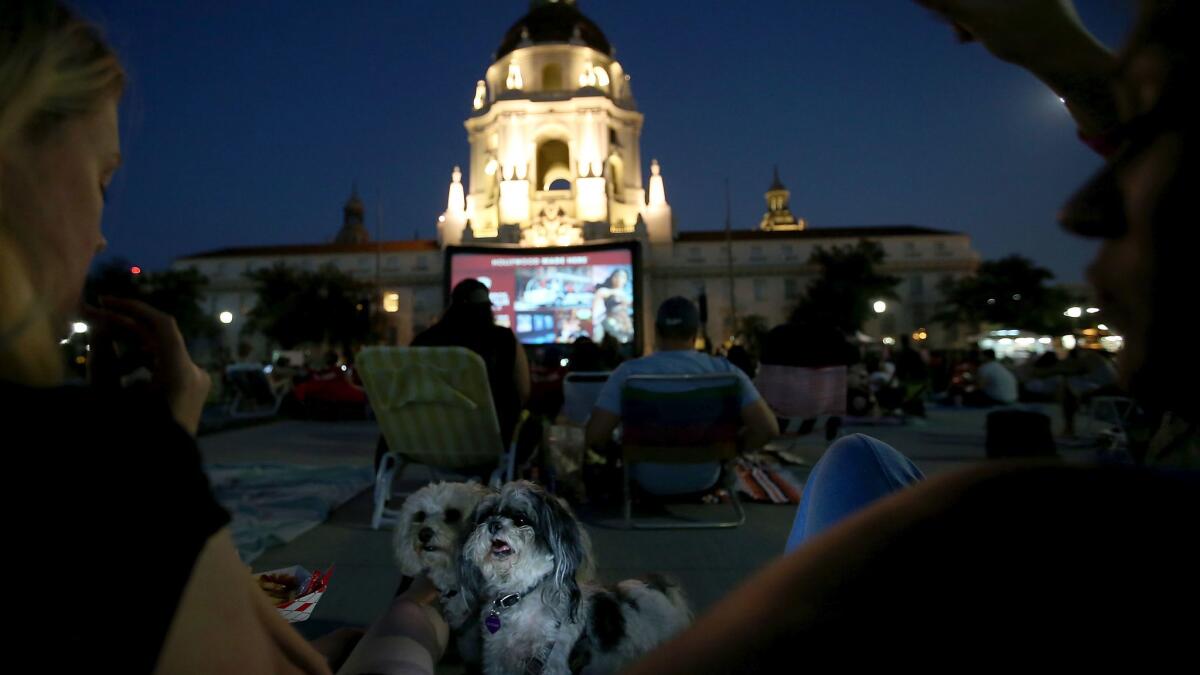 Beth Navarro, left, and Kristina Mitchell share a snack with Mitchell's dogs Oscar and Eloise during Eat See Hear's outdoor summer movie screening at Centennial Square in Pasadena.