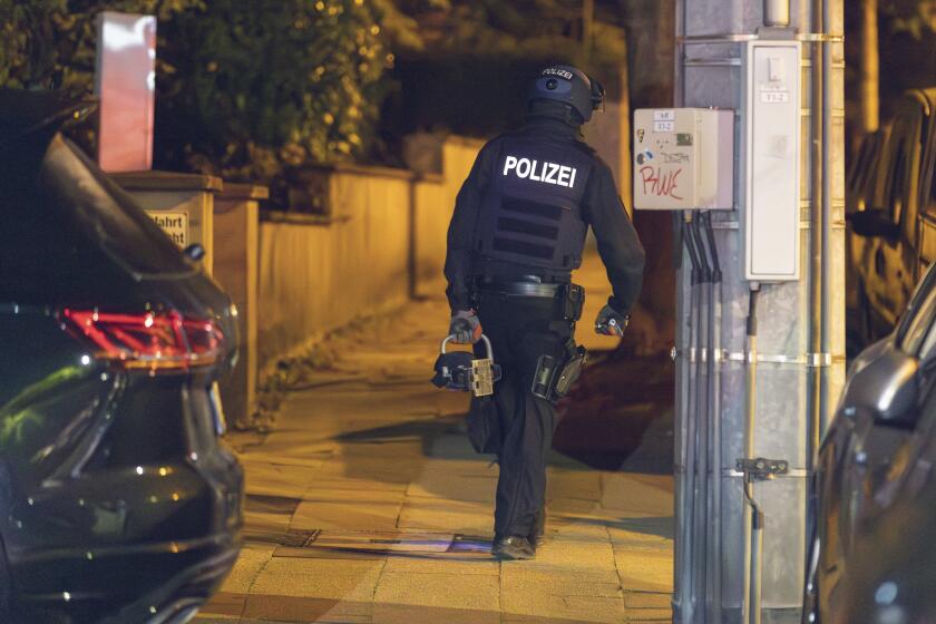A police officer wears a hydraulic door opener walks on duty in Essen, Germany Wednesday, Sept. 27, 2023. The German government on Wednesday banned a far-right, racist group known for its indoctrination of children as police raided dozens of homes of its members and other buildings early in the morning. (Justin Brosch/dpa via AP)
