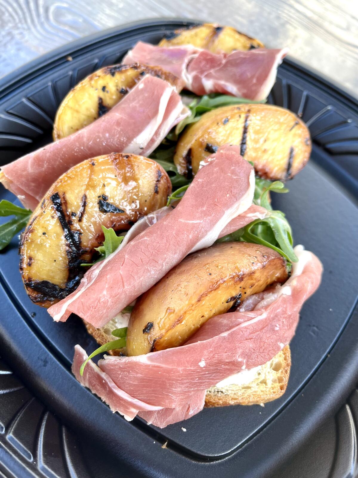 Grilled peach toast with ricotta-mascarpone spread and arugula salad on toasted sourdough.