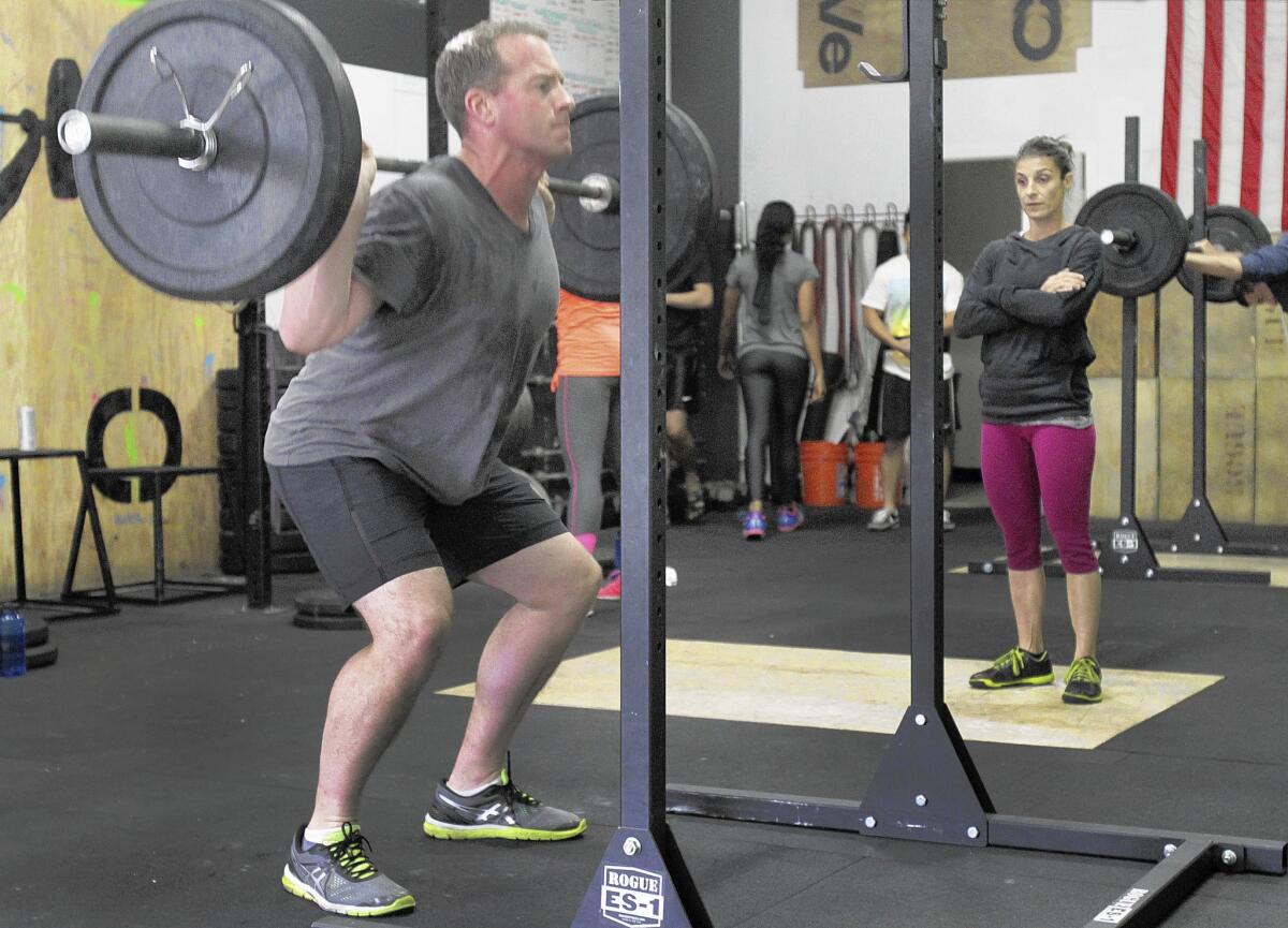 Craig Knight works out as coach Nikki Coletta watches at Cave CrossFit.