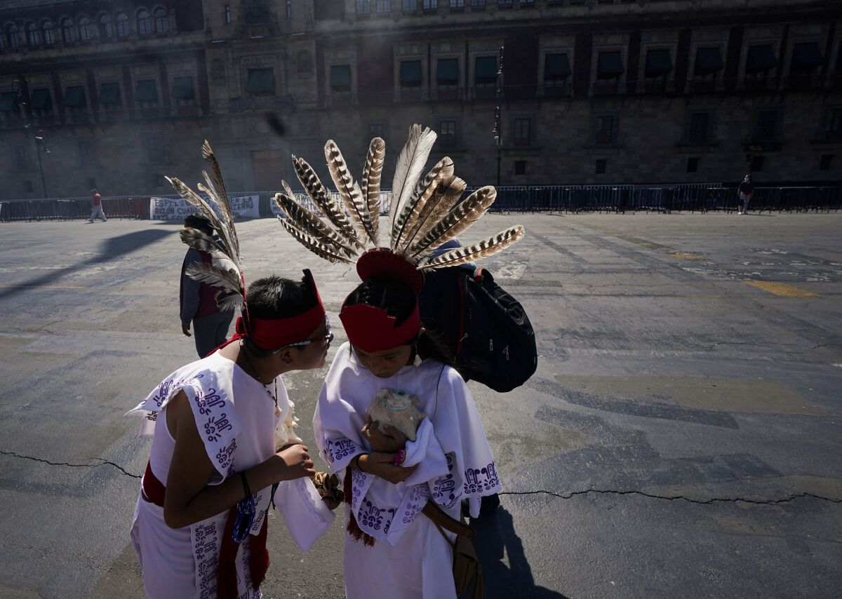 Two young dancers speak prior a performance as part of the commemoration marking the 700 year anniversary of the founding of the Aztec city of Tenochtitlan, known today as Mexico City, at Zocalo square in Mexico City, Monday, July 26, 2021, amid the new coronavirus pandemic. (AP Photo/Fernando Llano)