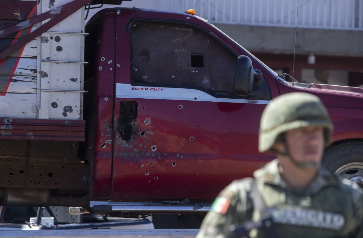 A soldier stands near a bullet ridden truck after a shootout in Parangaricutiro, Mexico,Thursday, March 10, 2022. Authorities in the avocado-growing zone of western Mexico said five suspected drug cartel gunmen have been killed in a massive firefight between gangs. ( AP Photo/Armando Solis)