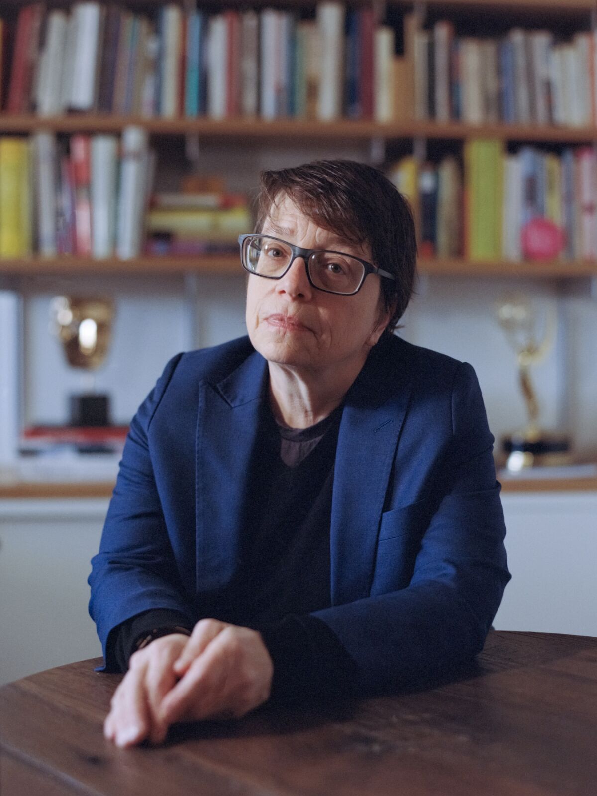 A woman with short hair and glasses, seated at a table.