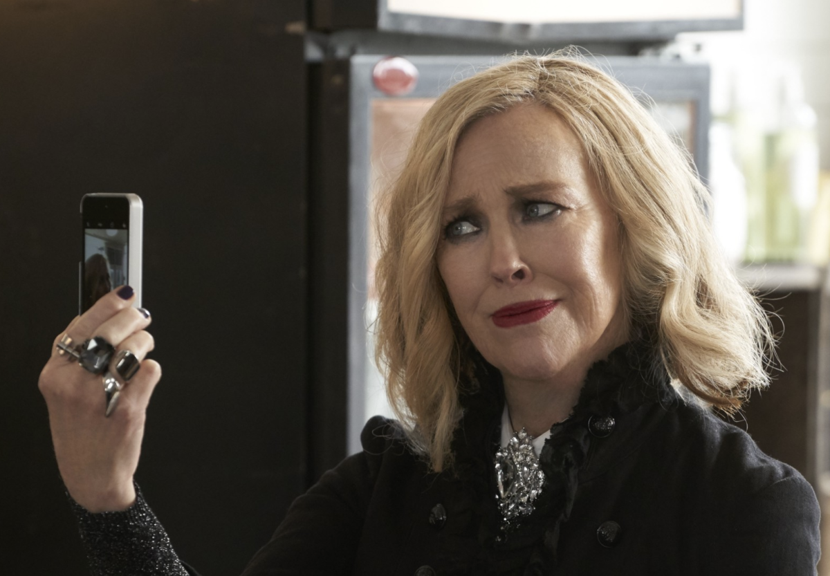 Catherine O'Hara looks at herself on her cell phone