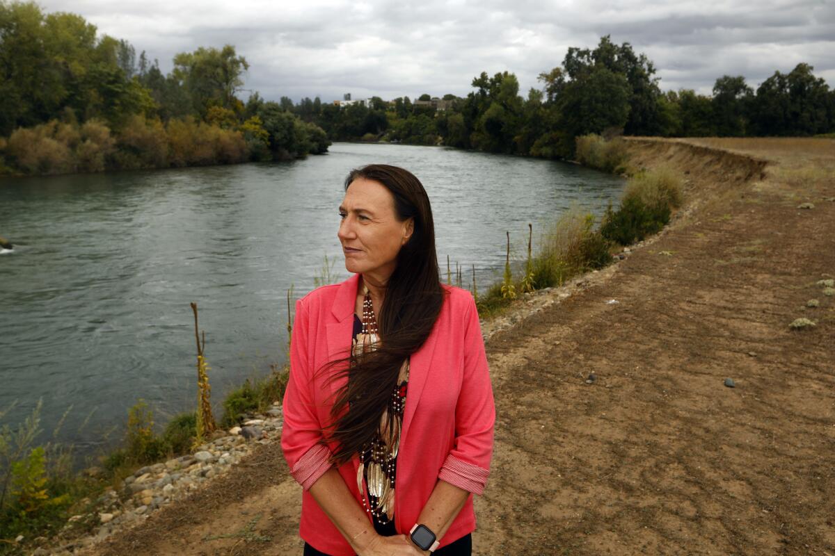 A woman standing near a river, looking into the distance