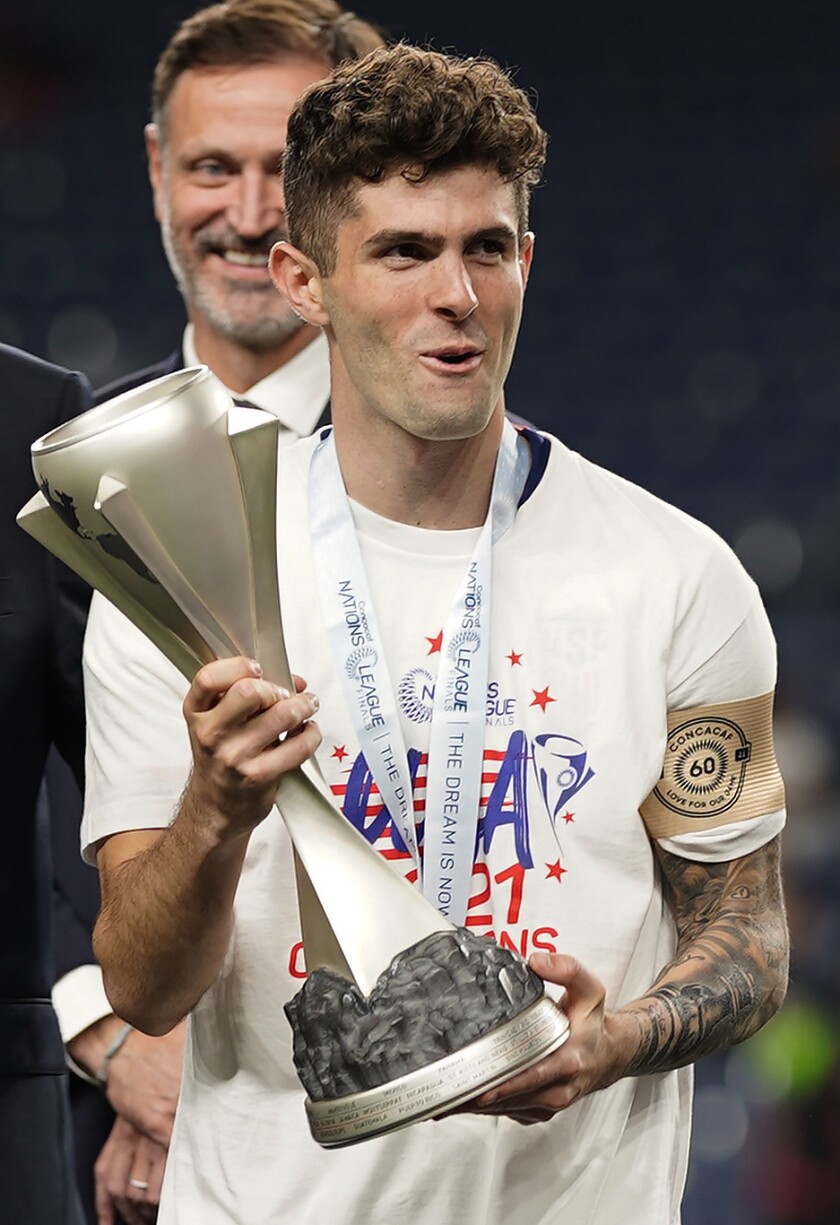 The United States' Christian Pulisic (10) holds the championship trophy while celebrating the Americans' win over Mexico 
