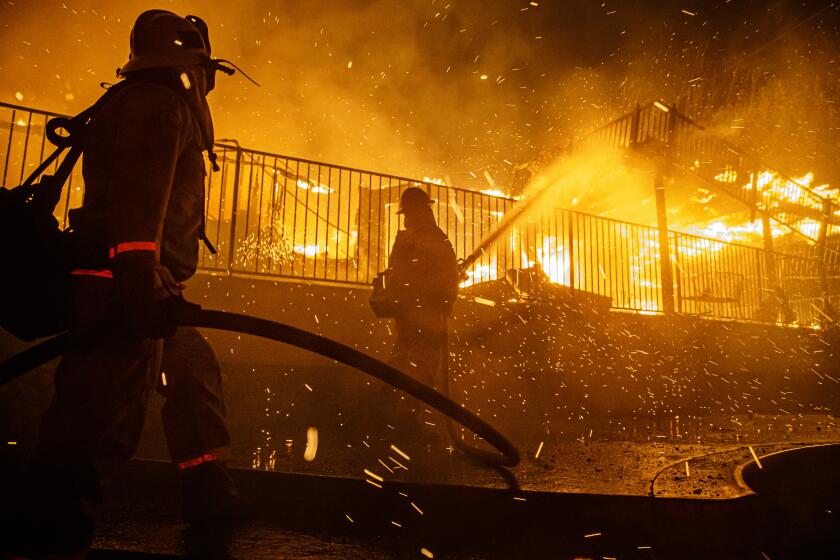 SAN BERNARDINO, CALIF. -- THURSDAY, OCTOBER 31, 2019: Firefighters work to control the flames from spreading as the embers blown by the wind threatens to burn other homes in the North Park neighborhood at the Hillside Fire in San Bernardino, Calif., on Oct. 31, 2019. (Marcus Yam / Los Angeles Times)