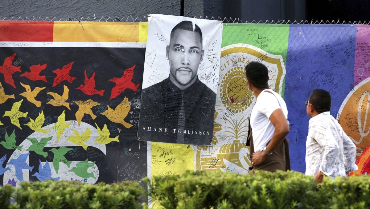 Visitors look at a memorial poster of Pulse nightclub massacre victim Shane Tomlinson at the closed club in Orlando, Fla., on Oct. 2, 2017, a day after the mass shooting Las Vegas.