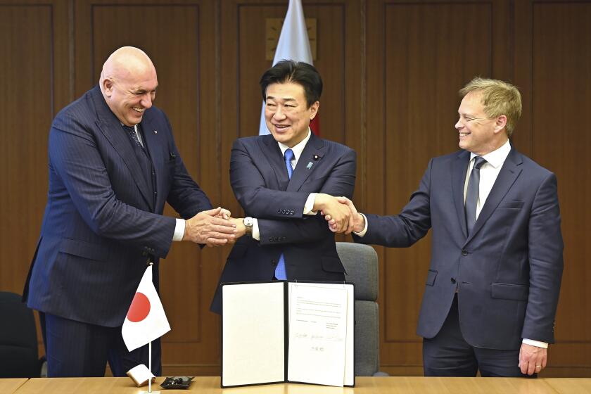 FILE - Britain's Defense Minister Grant Shapps, right, Italy's Defense Minister Guido Crosetto, left, and Japanese Defense Minister Minoru Kihara, center, shake hands after a signing ceremony for the Global Combat Air Programme (GCAP) at the defense ministry, Dec. 14, 2023, in Tokyo, Japan. Japan’s Cabinet on Tuesday, March 26, 2024, approved a plan to sell future next-generation fighter jets that it’s developing with Britain and Italy to other countries, in the latest move away from the country’s postwar pacifist principles. (David Mareuil/Pool Photo via AP, File)