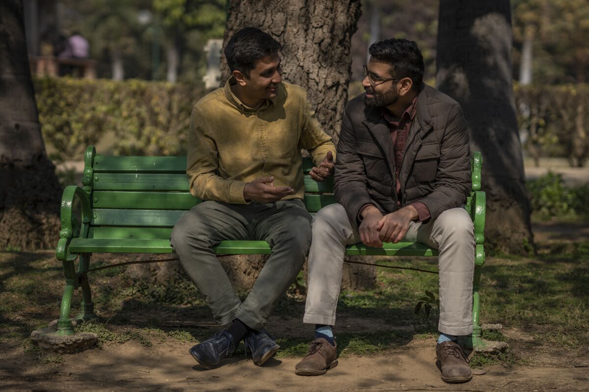 A gay Indian couple sitting on a park bench