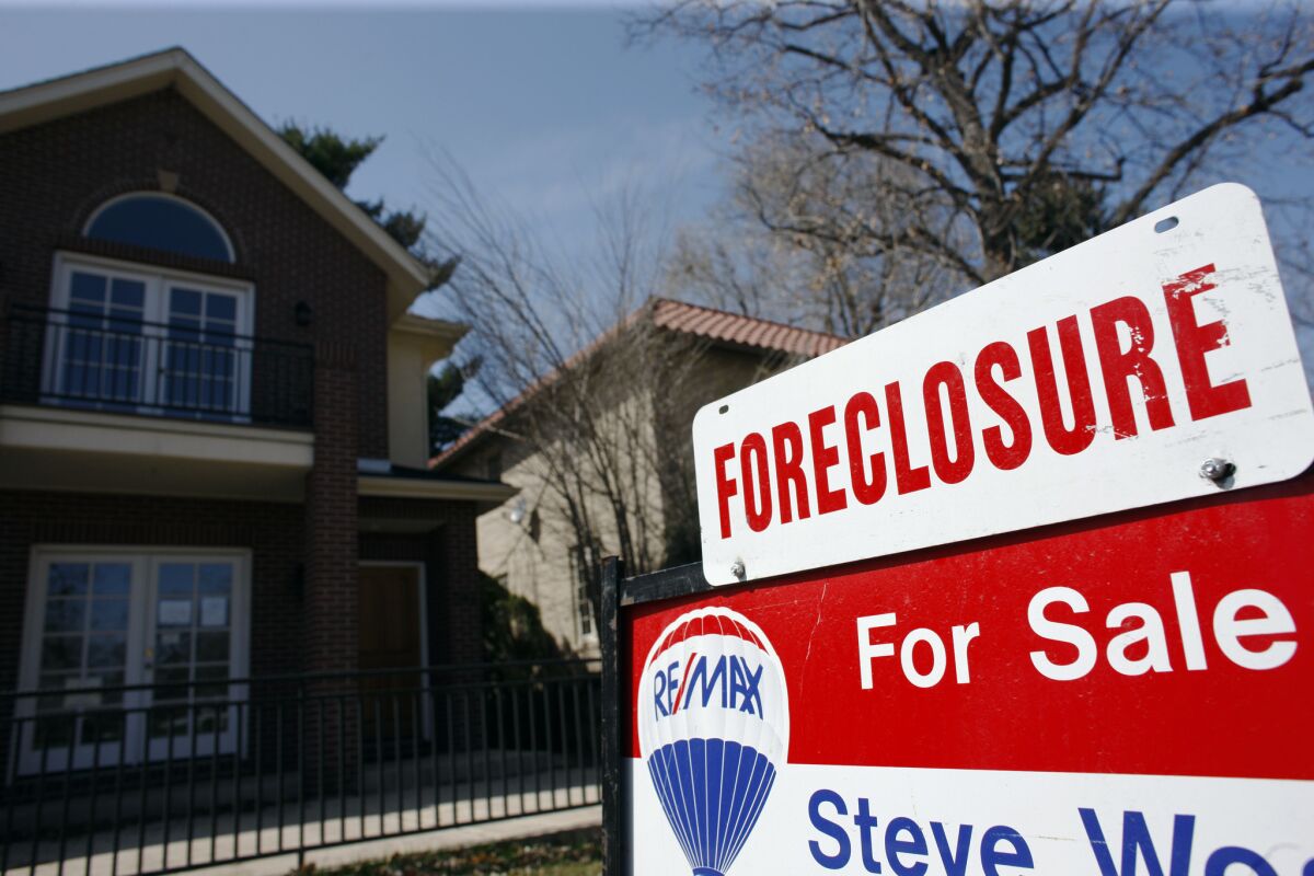 A foreclosure sign sits atop a for sale sign in front of a single-family in Denver, Colo. on April 4, 2010. To stop this harmful lending, the FHA should aim to cut its failure rate roughly in half, setting a maximum foreclosure rate of 10% on the loans it insures with an average foreclosure rate of 5%.