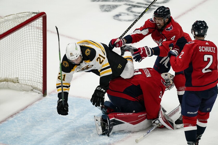 Boston Bruins left wing Nick Ritchie (21) falls over Washington Capitals goaltender Craig Anderson (31) with Capitals defenseman Brenden Dillon (4) nearby, during the second period of Game 1 of an NHL hockey Stanley Cup first-round playoff series Saturday, May 15, 2021, in Washington. (AP Photo/Alex Brandon)