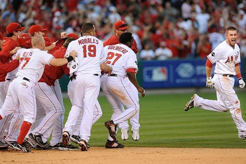 Angels catcher Jeff Mathis, right, is chased down by teammates after connecting on the game-winning hit against the Yankees in the 11th inning Monday against the Yankees in Game 3 of the American League Championship Series.