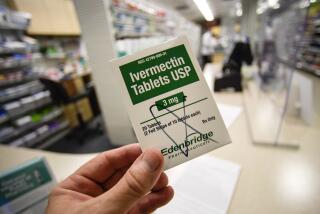 A box of ivermectin is shown in a pharmacy as pharmacists work in the background.