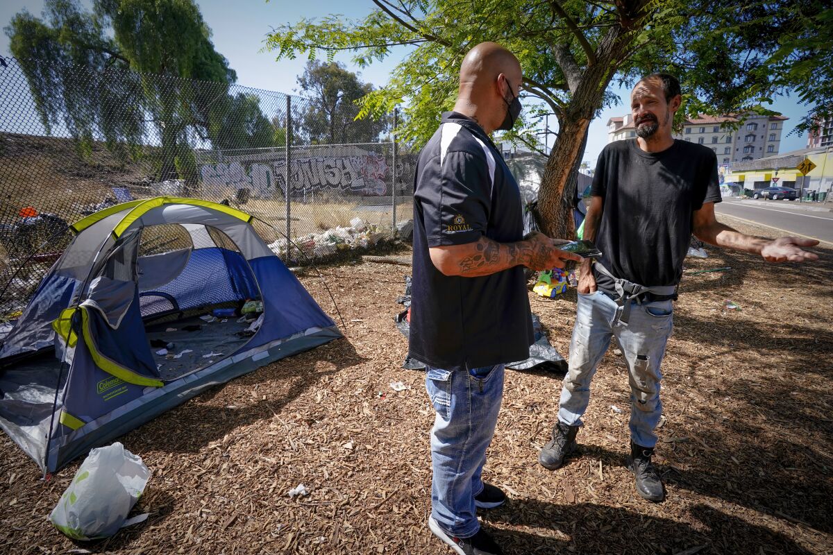 An outreach worker with Alpha Project spoke with Matt Tucker near his tent currently setup along the freeway offramp.
