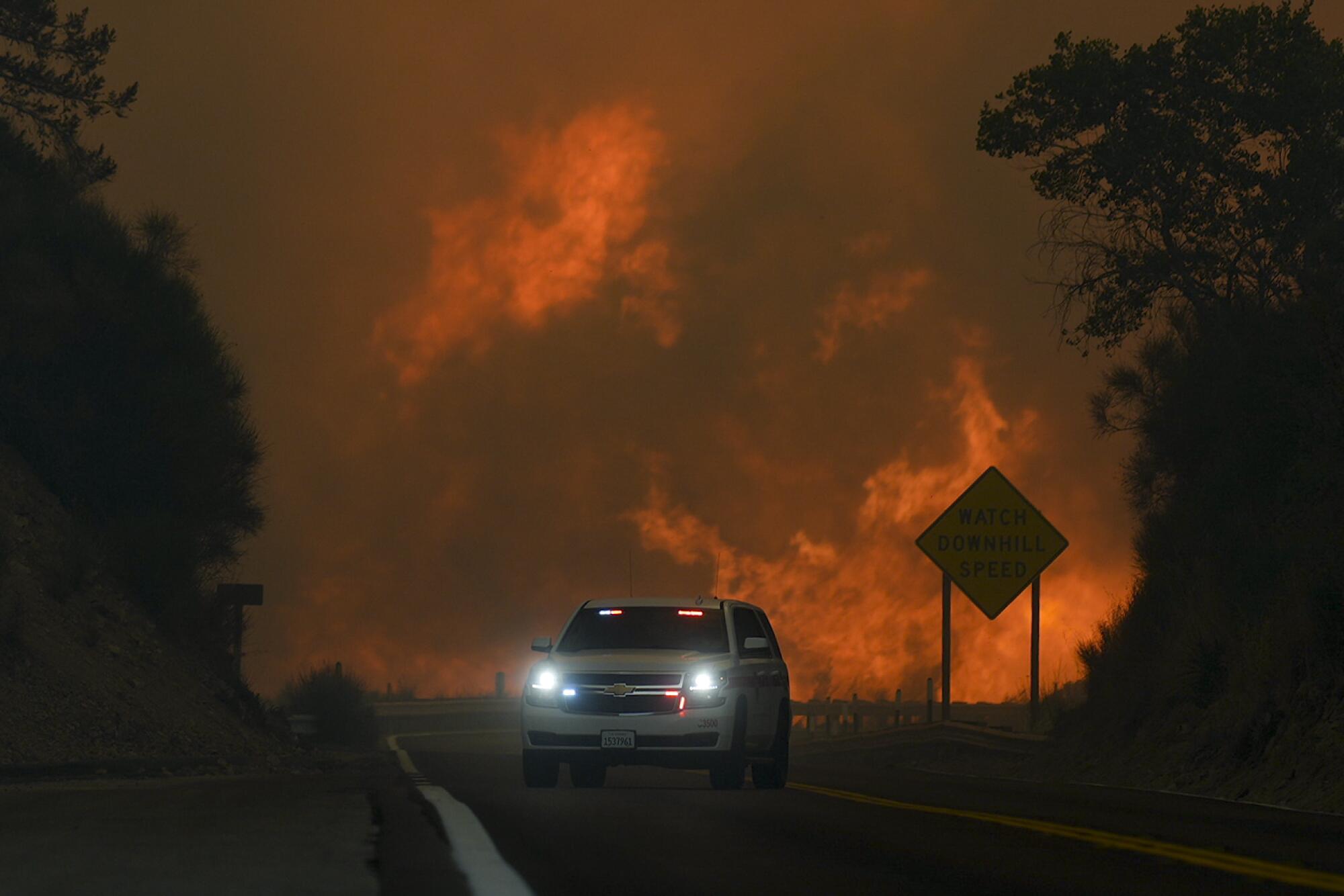 The Line Fire jumps Highway 330 as an emergency vehicle passes near Running Springs, California, on Saturday.