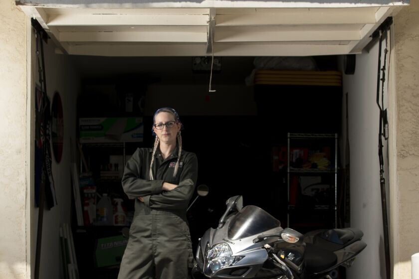 Talena Handley stands in her garage next to a motorcycle.