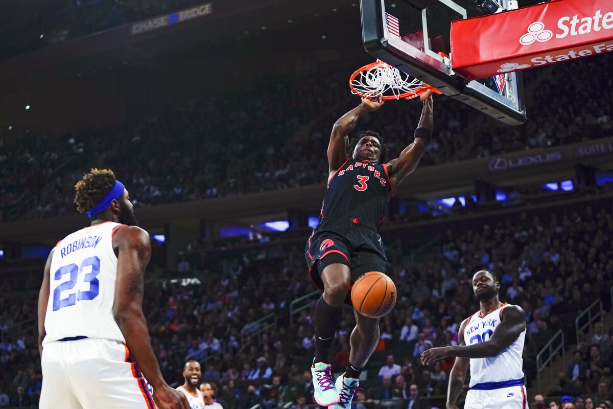 Toronto Raptors' OG Anunoby (3) dunks the ball in front of New York Knicks' Julius Randle (30) and Mitchell Robinson (23) during the first half of an NBA basketball game Monday, Nov. 1, 2021, in New York. (AP Photo/Frank Franklin II)