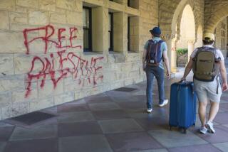 Students walk by graffiti near university president Richard Saller's office at Stanford University in Palo Alto, Calif., Wednesday, June 5, 2024. Stanford University said 13 people were arrested as law enforcement removed pro-Palestinian demonstrators who occupied a campus building early Wednesday that houses the university president and provost offices, with the school saying there was extensive damage inside and outside the building and an officer was lightly injured. (AP Photo/Nic Coury)