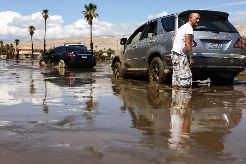 CATHEDRAL CITY, CALIFORNIA - AUGUST 21: A motorist whose car became stranded waits for a a bulldozer to clear mud from a road on August 21, 2023 in Cathedral City, California. Much of Southern California and parts of Arizona and Nevada are cleaning up after being impacted by Tropical Storm Hilary that brought several inches of rain that flooded roadways and winds that toppled trees and power lines across the region. (Photo by Mario Tama/Getty Images)