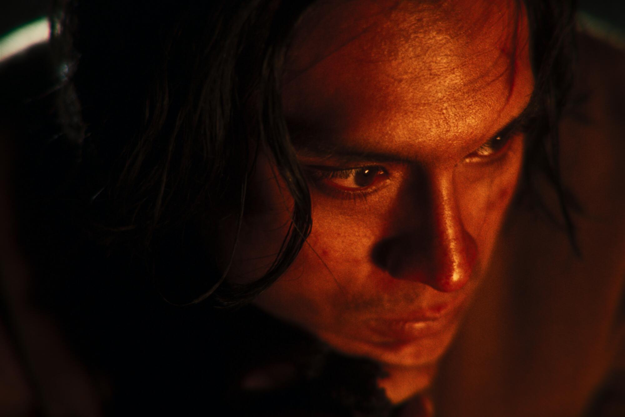 An indigenous person in closeup, lit as if by the glow of a fire