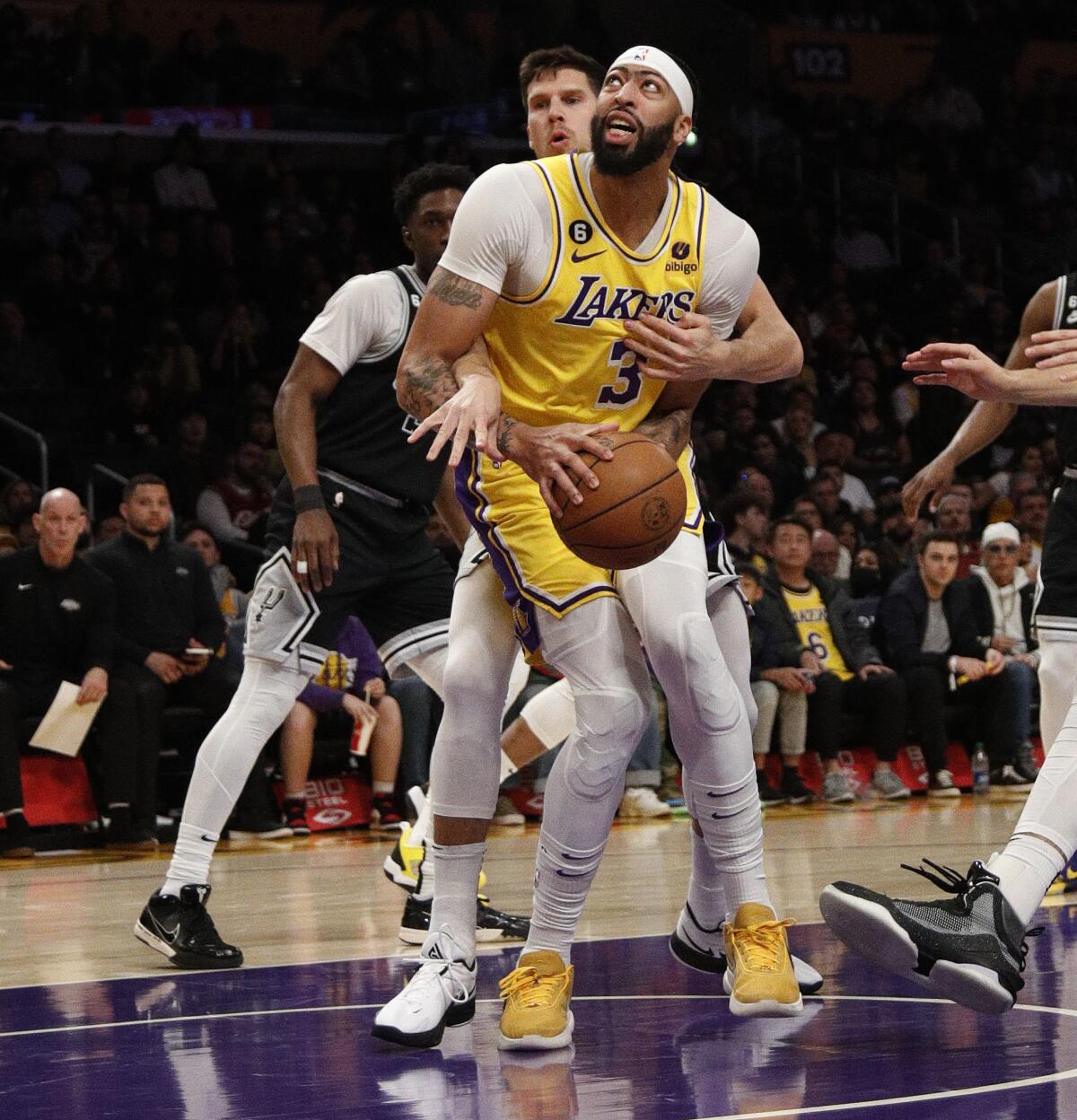 Lakers forward Anthony Davis gets wrapped up by San Antonio Spurs forward Doug McDermott.