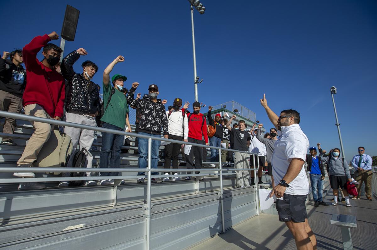 Costa Mesa's new head football coach Gary Gonzalez raises his hand in unison with his team during a meeting on Wednesday.