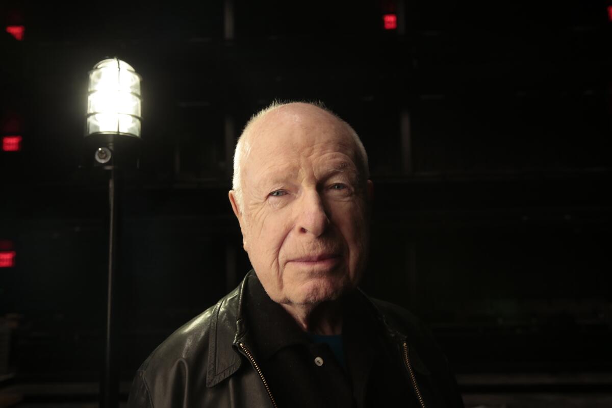 An older man with a stage light standing behind him.
