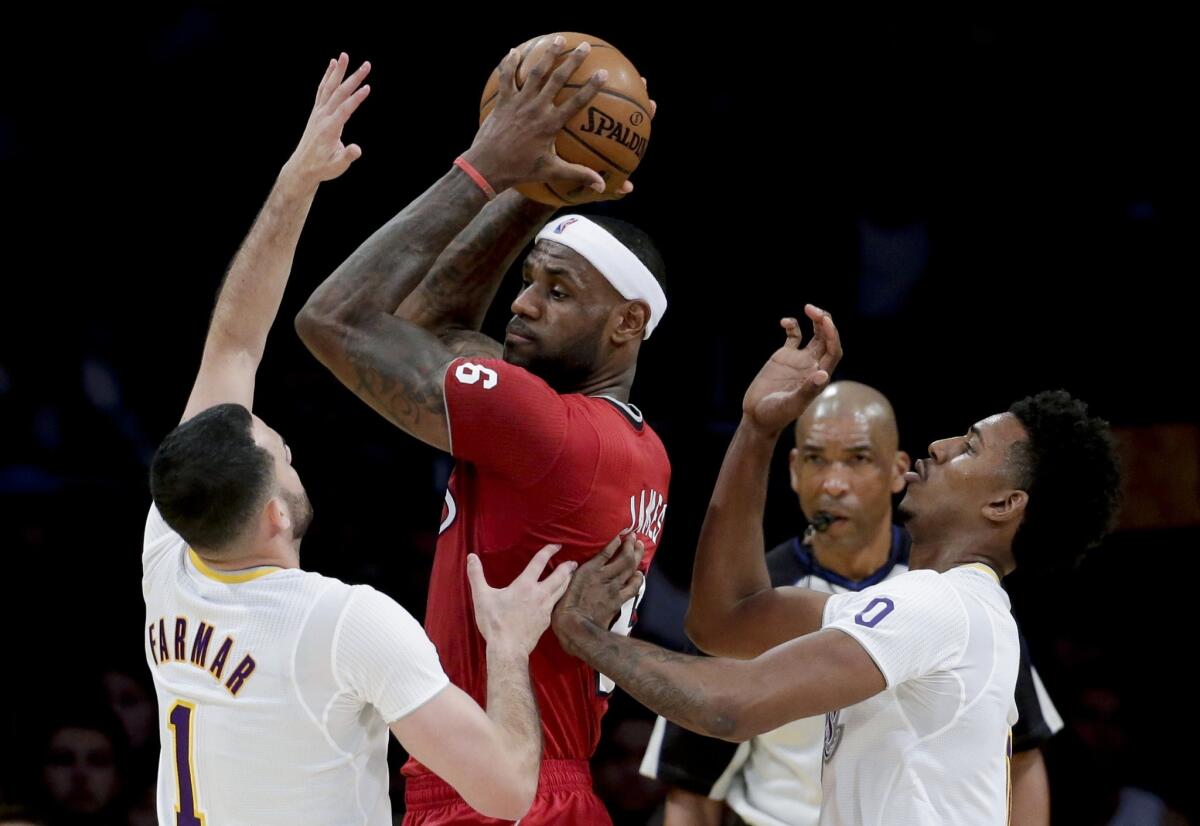 Heat forward LeBron James faces the double-team defense of Lakers guards Jordan Farmar, left, and Nick Young on Wednesday at Staples Center.
