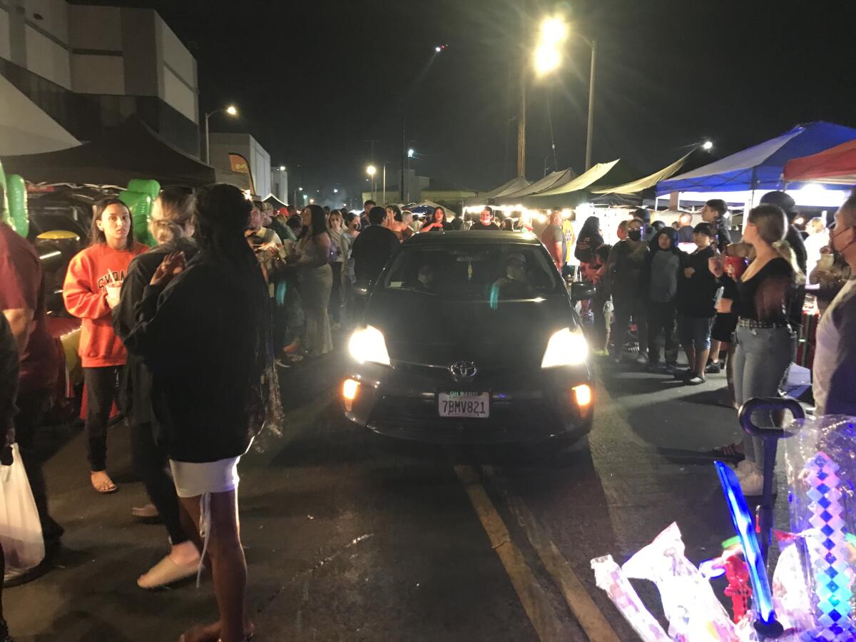 A car mixes with the crowd of customers and vendors at a recent Lincoln Heights night market.